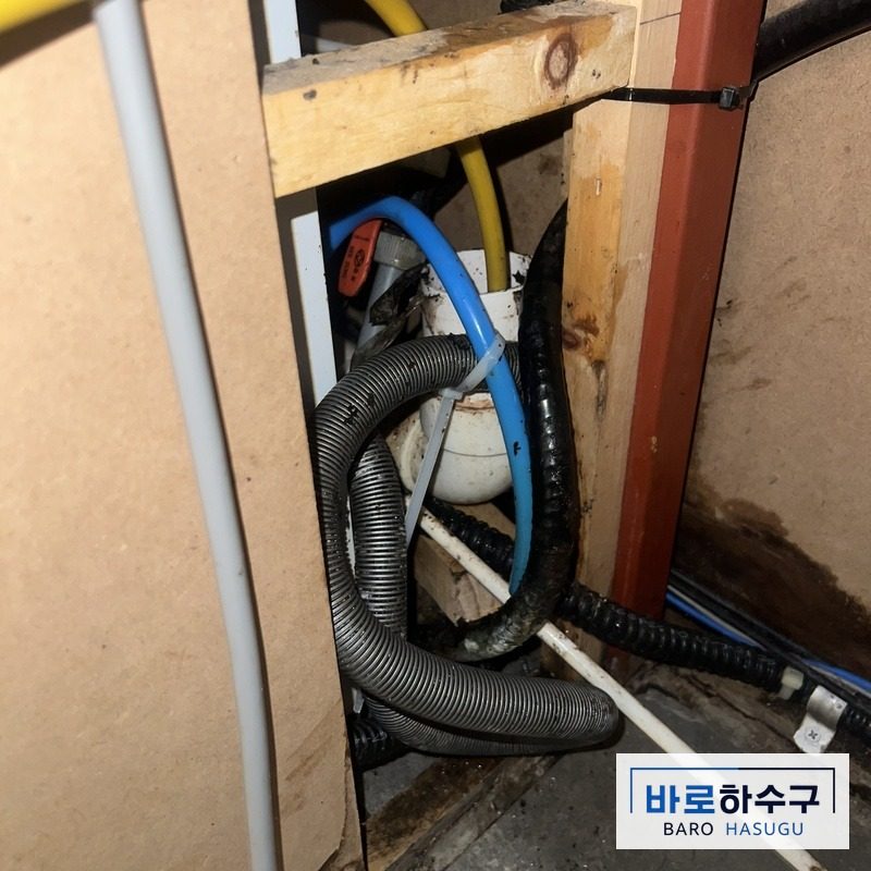 카페 하부장 배관에 노란 세척 장비 케이블을 넣어 작업하는 모습