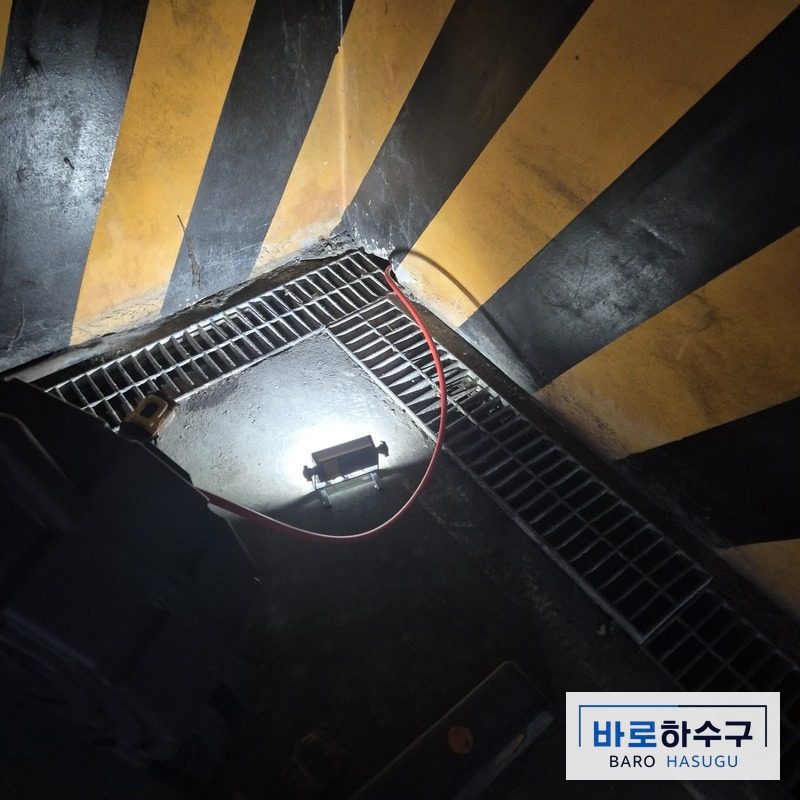 안산 단원구 지하주차장 트렌치 모서리 배관 쪽에 작업등을 넣고 세척하는 모습