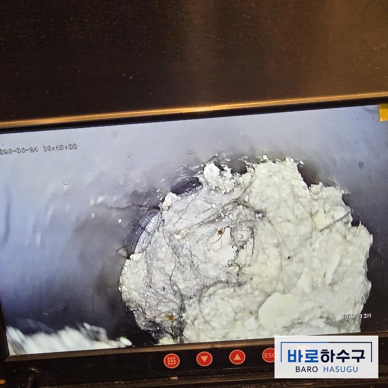 부평 현장 욕실 배관 내시경 화면, 하얗게 굳은 석회 덩어리가 관을 거의 막고 있는 작업 전 상태