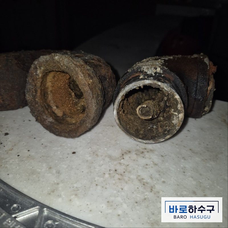 군포 현장 바닥에서 걷어낸 기존 주철 배관 단면, 녹과 찌꺼기가 관 안쪽을 두껍게 덮은 작업 전 상태