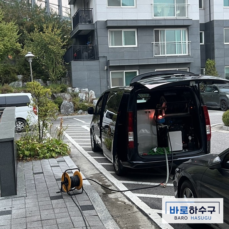아파트 단지 안에 고압세척 장비 차량을 대고 호스를 펼친 작업 준비 모습